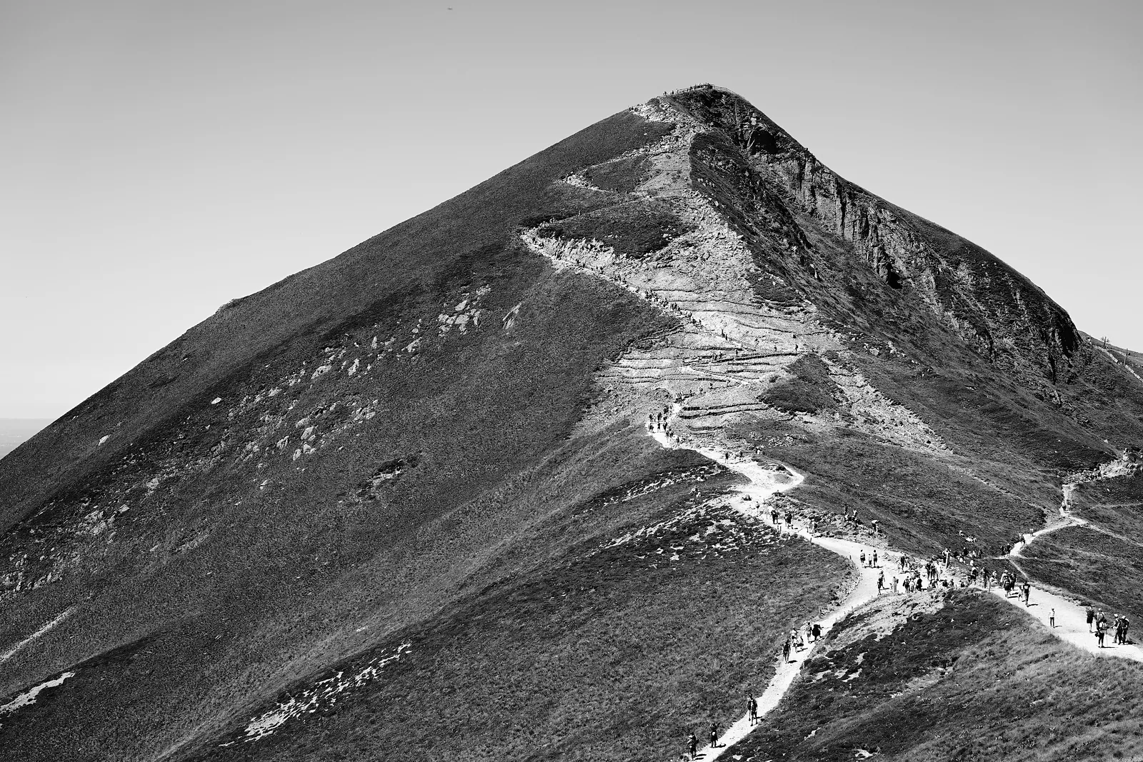 Sommet en pyramide, un sentier et des marcheurs minuscules sur l'arête
